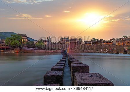 Tourists People Crossing Waters On Stepping Stones On Tuojiang River, Flowing Through The Centre Of 