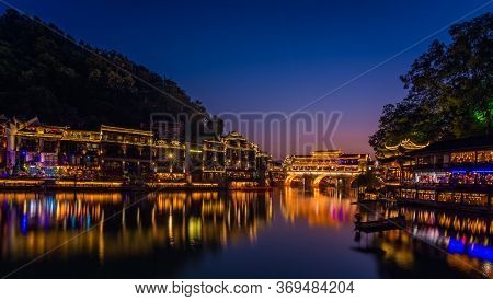Illuminated At Night Old Historic Arched Bridge On The Riverbanks Of Tuo River, Flowing Through The 