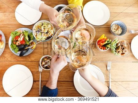 Group Of Crop Anonymous Friends Clinking Glasses With Wine While Gathering Around Table With Delicio