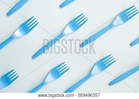 Many Blue Plasic Forks On Light Background, Top View. Disposable Tablewear, Sorting Plastic Concept.