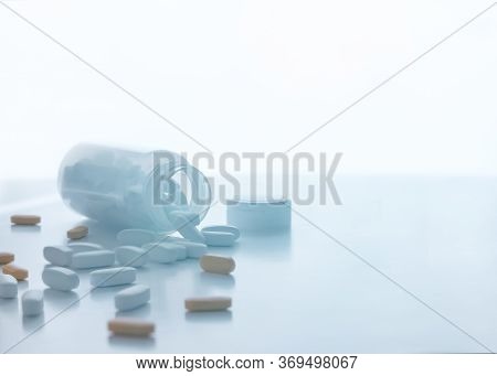 Pills Spilling Out Of A Pill Bottle On White. With Copy Space. Medicine Concept. Trand Tinted Image