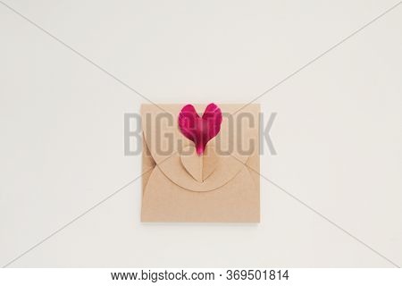 Petals Of Dark Red Peony In Shape Of Heart With Craft Envelope On White Background. Blank Card For I