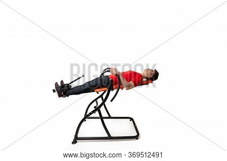 Man Doing Exercise On Inversion Table For His Back Pain, Isolated On White