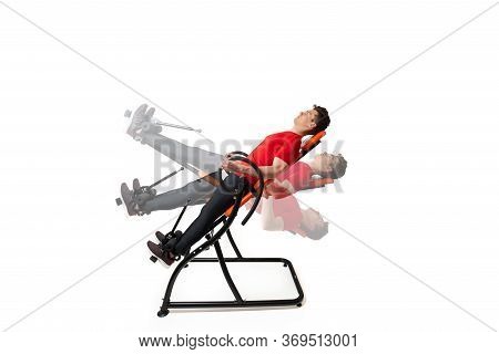 Man Doing Exercise On Inversion Table For His Back Pain, Isolated On White