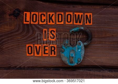 Lockdown Is Over Sign, Open Iron Lock On Wooden Background. Opening Borders Between Countries. End O