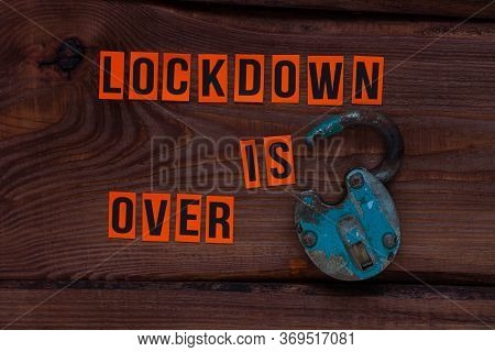 Lockdown Is Over Sign, Open Iron Lock On Wooden Background. Opening Borders Between Countries. End O