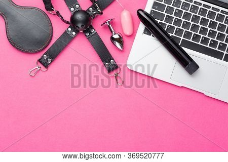 Adult Webcam And Virtual Sex Chat Concept. Laptop With Dildo, Vibrator Egg, Buttplug And Gag On Red 