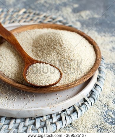 Raw Uncooked Fonio Seeds With A Spoon On A Plate On Grey Background Close Up