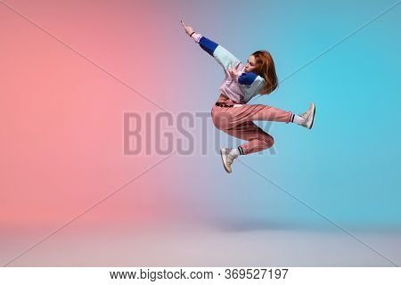 In Jump. Beautiful Girl Dancing Hip-hop In Stylish Clothes On Colorful Gradient Background At Dance 