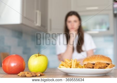 The Choice Between Unhealthy And Healthy Food. Burger And French Fries In Front Of An Apple, Tomato 