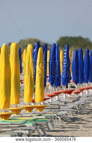 Yellow And Blue Umbrellas On The Beach All Closed Due To The Economic Crisis