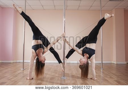 Two Young Girls Train Pole Dance And Do A Synchronous Trick Together, Gymnasts Hang On A Pylon In Th