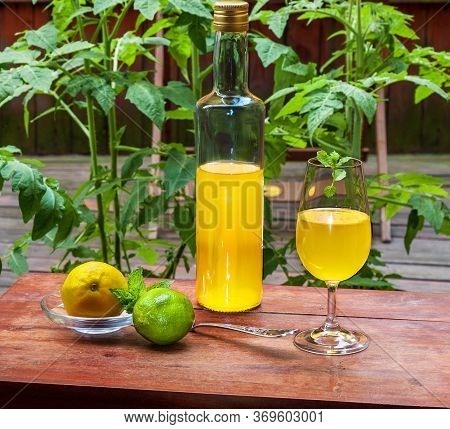 Working From Home With Limoncello In Glass, Bottle Of Sweet Italian Lemon Liqueur, Laim And Lemon On