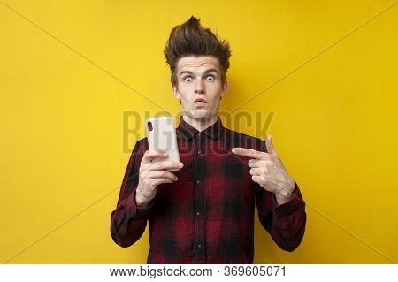 Shocked Guy With Funny Hairstyle Use Smartphone On Yellow Isolated Background, Hipster Holds Phone A