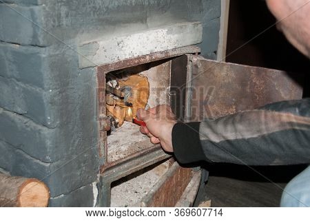 Man Kindle A Fire In The Fireplace With A Lighter. Vintage Fireplace In The Country House. Firewood.