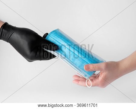 A Hand Gives A Medical Mask To Protect The Face Of Another Person