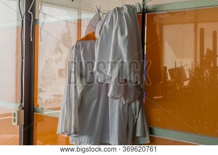 Collection Of Dirty Chef's Uniforms Hanging On Rope Inside Abandoned Bankrupt Resort.
