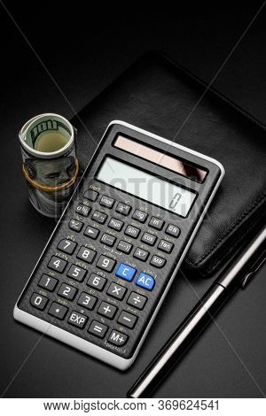 calculator and a roll of us dollarts on desk.