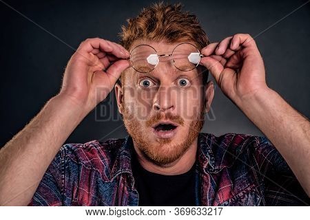 Headshot Of Shocked And Impressed Overwhelmed Redhead Guy With Beard, Taking Off Glasses And Holding