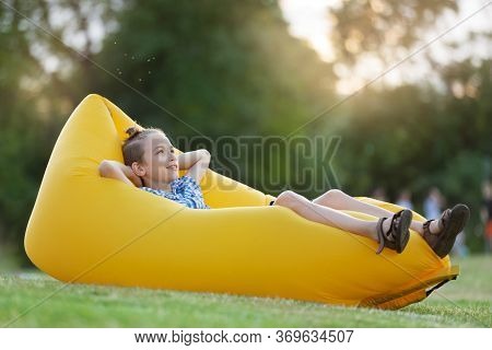 Boy Resting In Nature, Lies On A Yellow Air Sofa, Concept