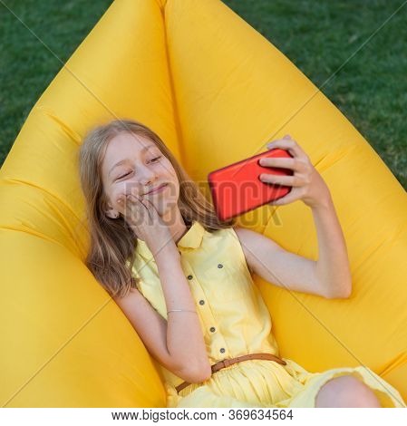 Girl Relaxing In Nature, Lies On An Air Sofa And Takes A Selfie, Showing Emotions