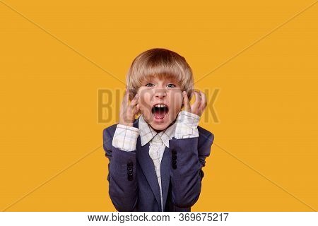 A Little Handsome Blond Boy Screams With Horror And Smiles At The Camera.