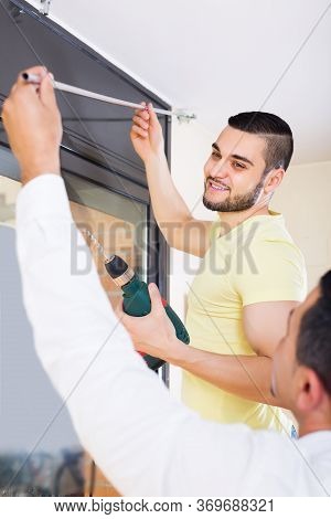 Two Positive Male Adults Putting Corbel At Residential Kitchen