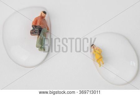Miniature People Get Drowned In Drops Of Water On White Background. Macro Photography Concept Idea F