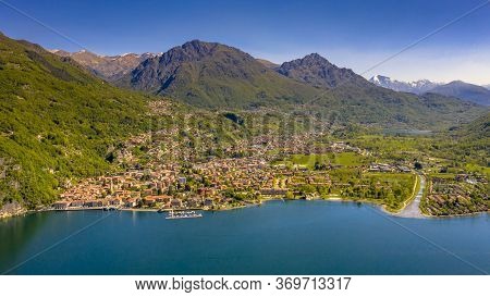 Aerial View Of City Of Porlezza On The Shore Of Lake Lugano With The Alps In The Background Seen Fro