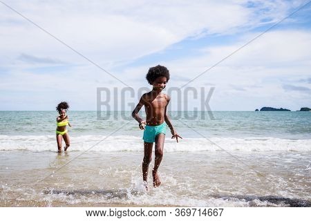 African American, Kids Group In Swimwear Enjoying Running To Play The Waves On Beach. Ethnically Div
