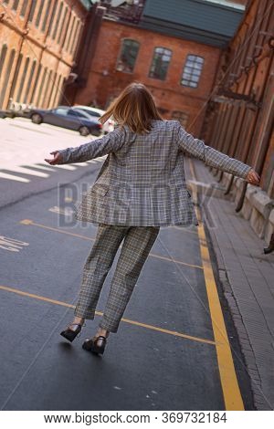 Unrecognizable Blond Lady Wearing Plaiding Trouser Suit Going And Jumping Anong The Street With Red 