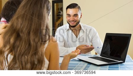 Positive Smiling Salesman And Young Couple At Home Talking About Purchase