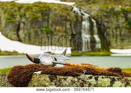 Viking Helmet With Axe On Lake Shore In Norway. Tourism And Traveling Concept
