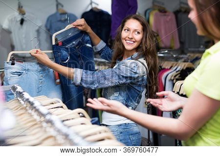 Happy Young Girl Buying Pants In Clothing Store