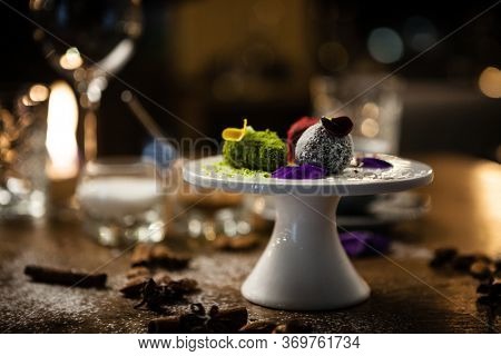 Vegan truffles dessert made of dates, almound and peanut butter on a plate. Delicious healthy food closeup served for lunch on a table in modern gourmet cuisine restaurant.