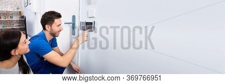 Alarm System Security Installation At Home. Technician Installing Near Door