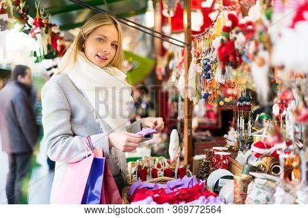 Portrait Of Female Customer Near Counter With Christmas Gifts And Garlands