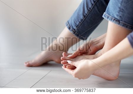 Tired Woman Doing Self Foot Massage For Pain Relief After Fatigue, Long Walking, Working, Standing, 