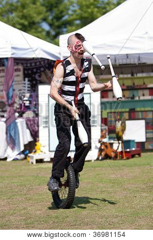 Cirkus Performer jonglerer mens ridning unicykel