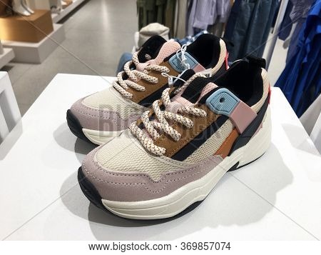 White Platform Sneakers With Bright Color Accents On Shelf In Shoes Store. Mass Market Shop. Close V