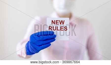 Text New Rules Written On Note Paper In Hands Of A Blurred Doctor In Gloves And Mask. New Rules Afte