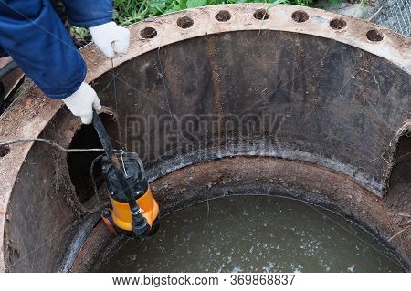 Immersion Of The Drainage Pump In A Cesspool Filled With Contaminated Water With Feces, Pumping Of H