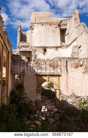 Abandoned Old Ruined Building. Gate With An Arc Without Door. Ruined Facade Of The Walls. Wild Growi