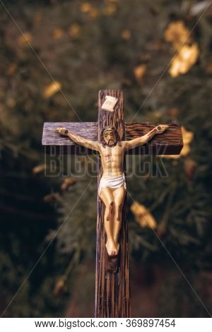 Beautiful Old Wooden Crucifix With Dust And Spiderweb In A Backdrop Of Garden With Cosmos Flowers.