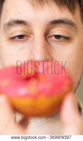 Man With Donut. Pink Bad Fat Doughnut In The Hands Of A Man. A Quick Snack, Excess Cholesterol