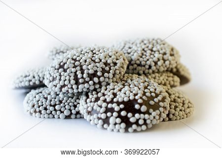 A Bunch Of Dark Chocolate Nonpareils On White Background