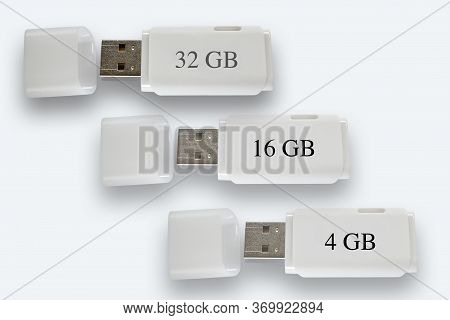 White Usb Memory Sticks, 4 Gb, 16 Gb And 32 Gb On White Background, With Their Lids Off