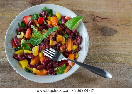Closeup On Red Kidney Beans And Bell Pepper Salad Served On Tan Plate On Wooden Table, Decorated Wit