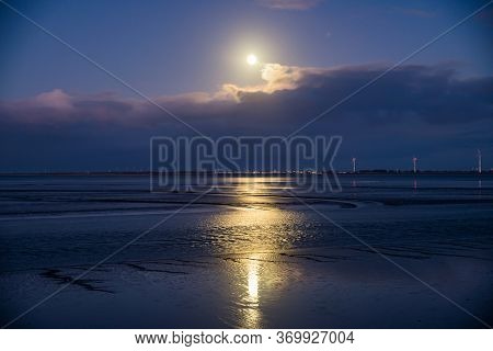 Low Tide In Delfzijl During Full Moon With The View On Wind Electricity With Germany On The Opposite