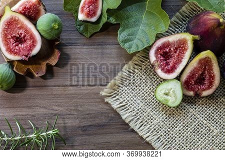 Figs, green leaves on rustic wooden background